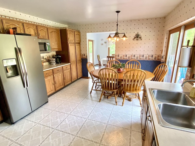 3561 Barber Rd, Hastings, MI 49058 - kitchen featuring appliances with stainless steel finishes, wallpapered walls, a sink, healthy amount of natural light, and decorative light fixtures