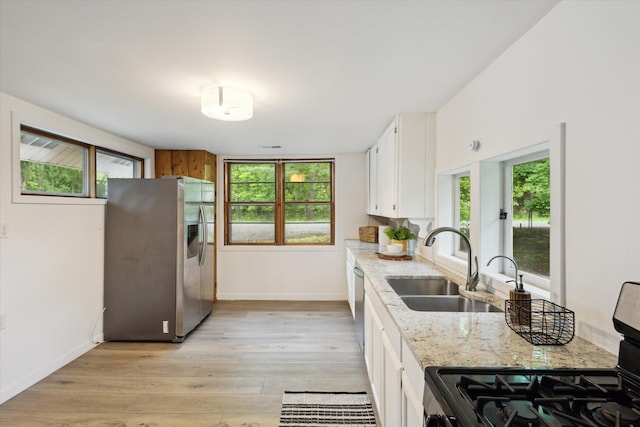 6780 Packer Dr NE, Belmont, MI 49306 - kitchen with stainless steel appliances, a sink, white cabinets, baseboards, and light wood-type flooring