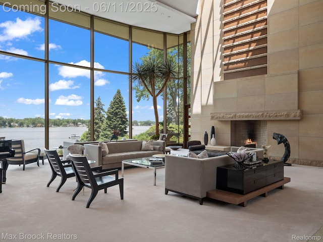 4790 Dow Ridge Rd, Orchard Lake, MI 48324 - living area featuring expansive windows, a high ceiling, a water view, a fireplace, and carpet