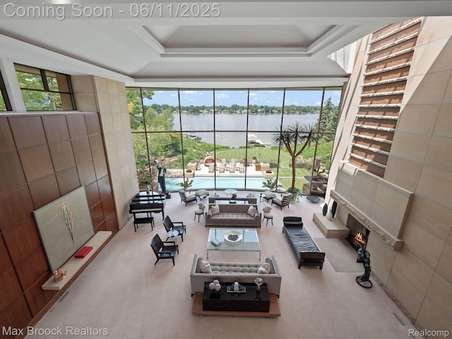 4790 Dow Ridge Rd, Orchard Lake, MI 48324 - carpeted living area with expansive windows, a water view, a tray ceiling, and a fireplace