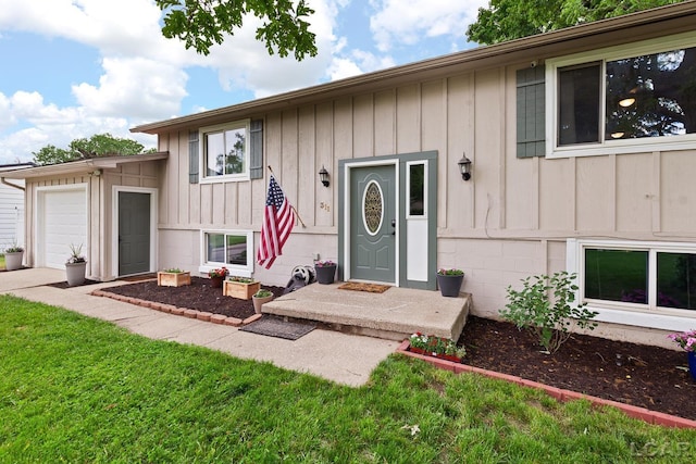 311 Marion St, Clinton, MI 49236 - view of exterior entry with board and batten siding, an attached garage, and a yard
