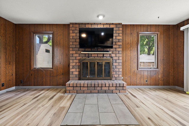 3618 Grape Ave NE, Grand Rapids, MI 49525 - unfurnished living room featuring wood finished floors, plenty of natural light, a brick fireplace, baseboards, and wooden walls