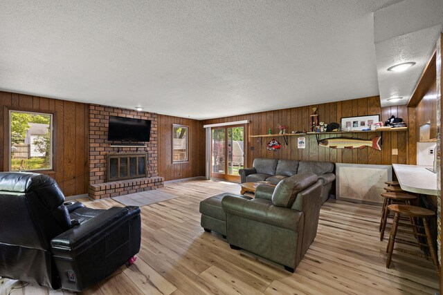 3618 Grape Ave NE, Grand Rapids, MI 49525 - living room with a textured ceiling, wood walls, a fireplace, and light wood-style flooring