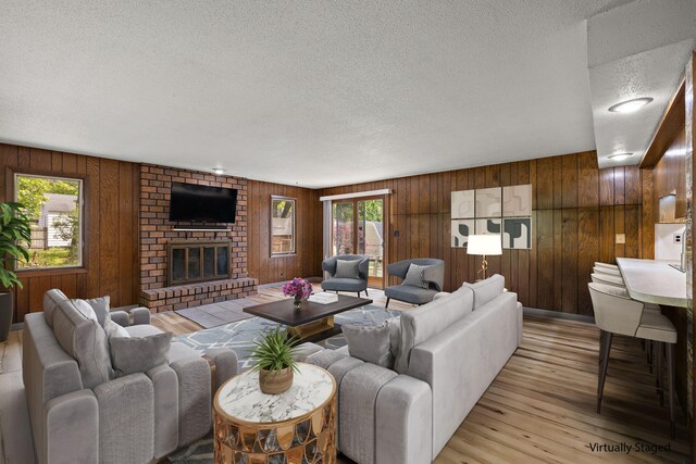 3618 Grape Ave NE, Grand Rapids, MI 49525 - living room with a textured ceiling, light wood-style floors, wood walls, and a fireplace