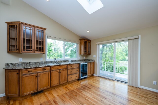 2310 Riverbend Dr, Benton Harbor, MI 49022 - kitchen with wine cooler, brown cabinetry, light wood-style floors, lofted ceiling, and light stone counters