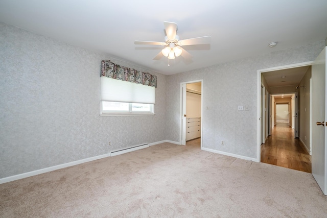 2310 Riverbend Dr, Benton Harbor, MI 49022 - unfurnished bedroom with carpet, a baseboard radiator, a walk in closet, a ceiling fan, and baseboards