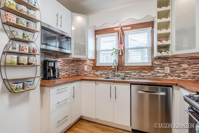 1836 Silver Ave SE, Grand Rapids, MI 49507 - kitchen featuring wood counters, stainless steel appliances, a sink, white cabinetry, and decorative backsplash