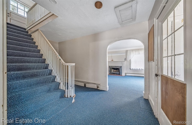 326 W Iroquois Rd, Pontiac, MI 48341 - staircase featuring a baseboard radiator, carpet, arched walkways, a fireplace, and a textured ceiling