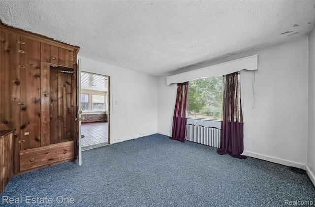 326 W Iroquois Rd, Pontiac, MI 48341 - empty room featuring a textured ceiling, dark carpet, and baseboards