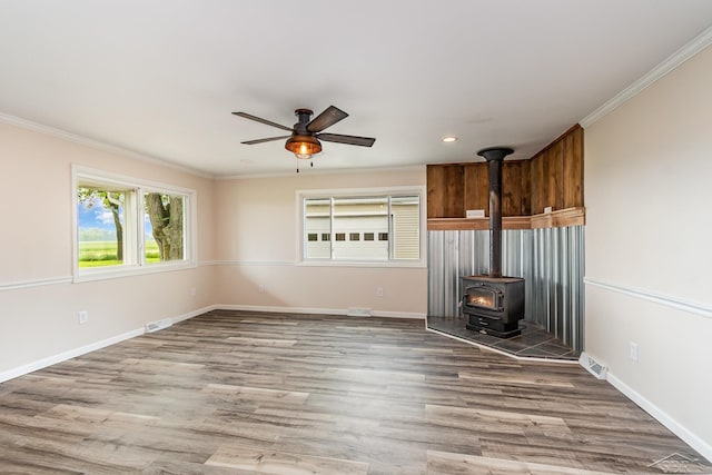 6835 Hackett Rd, Freeland, MI 48623 - unfurnished living room featuring a wood stove, ceiling fan, ornamental molding, wood finished floors, and recessed lighting