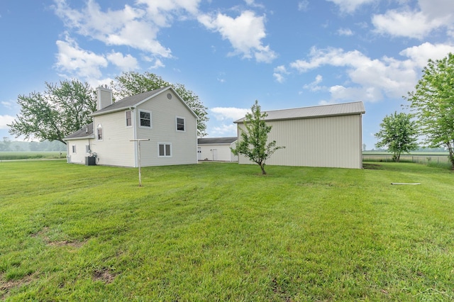 6835 Hackett Rd, Freeland, MI 48623 - rear view of house with a chimney, a lawn, a pole building, and an outbuilding