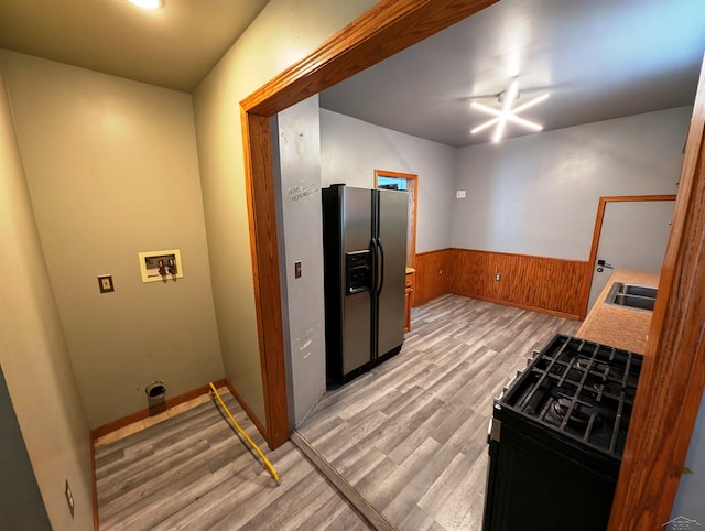 208 State St, Bay City, MI 48706 - kitchen with stainless steel refrigerator with ice dispenser, light wood finished floors, a wainscoted wall, wood walls, and black range with gas cooktop