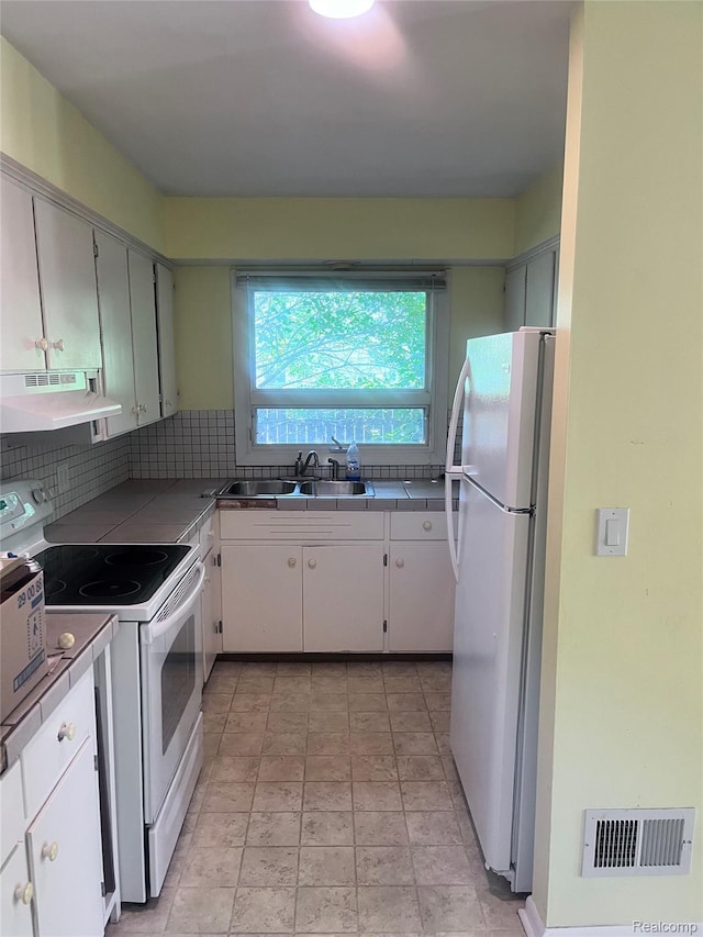140 Pershing Dr NE, Grand Rapids, MI 49505 - kitchen with white appliances, under cabinet range hood, tile countertops, tasteful backsplash, and white cabinetry