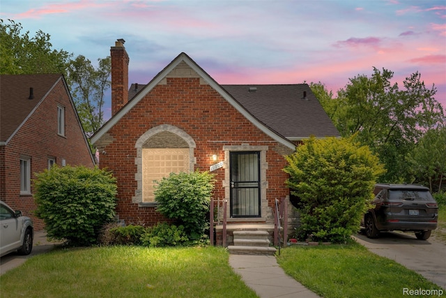 19200 Goulburn St, Detroit, MI 48205 - view of front of home with a chimney, brick siding, roof with shingles, and a yard