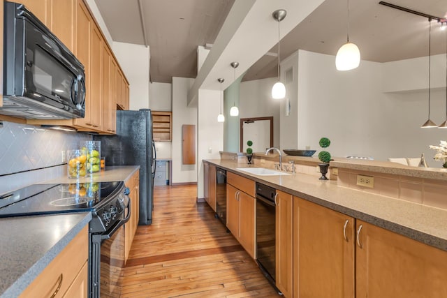 109 W Washington Ave Unit 16, Jackson, MI 49201 - kitchen featuring black appliances, a sink, light wood finished floors, tasteful backsplash, and pendant lighting