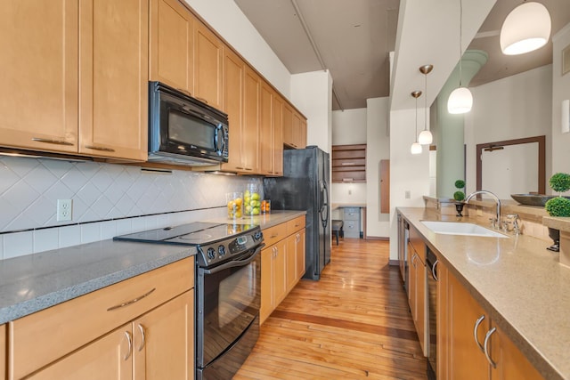 109 W Washington Ave Unit 16, Jackson, MI 49201 - kitchen with black appliances, a sink, light wood finished floors, backsplash, and light stone counters