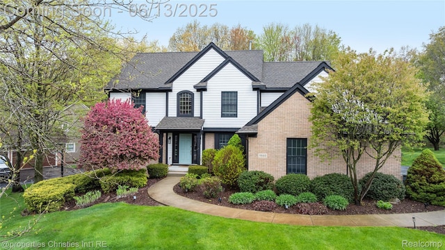 9840 Oak Valley Dr, Clarkston, MI 48348 - traditional-style home with brick siding, a front lawn, and a shingled roof