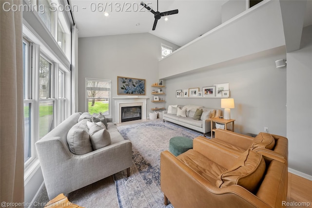 9840 Oak Valley Dr, Clarkston, MI 48348 - living room with high vaulted ceiling, a glass covered fireplace, a ceiling fan, wood finished floors, and baseboards