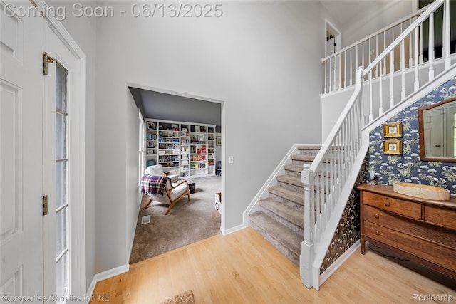 9840 Oak Valley Dr, Clarkston, MI 48348 - stairway with wood finished floors, a high ceiling, and baseboards