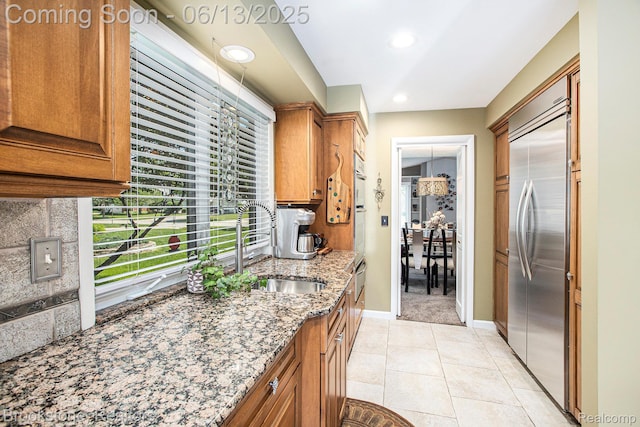 4057 Cypress Dr, Troy, MI 48085 - kitchen with stainless steel built in fridge, a sink, light stone counters, brown cabinets, and baseboards