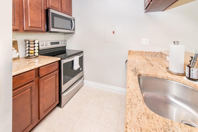 855 S Pontiac Trl Unit A305, Walled Lake, MI 48390 - kitchen featuring stainless steel appliances, baseboards, a sink, light tile patterned floors, and light stone counters