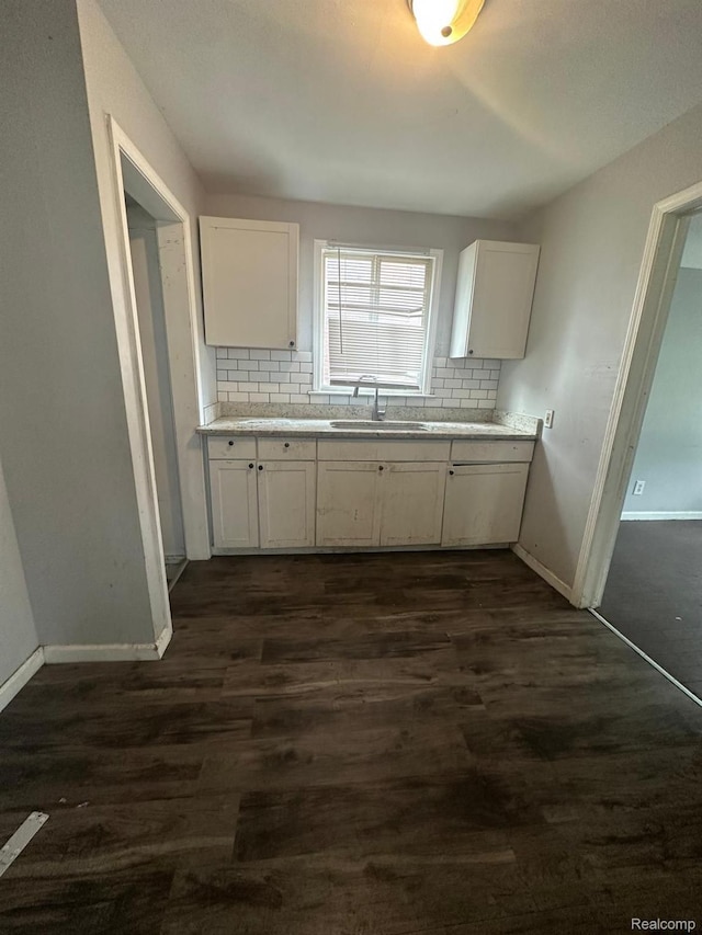 9317 Ward St, Detroit, MI 48228 - kitchen featuring a sink, decorative backsplash, white cabinetry, and baseboards