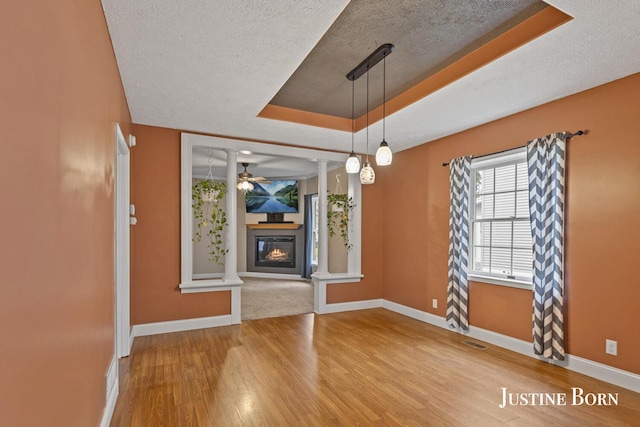 2264 Stafford Ave SW, Grand Rapids, MI 49507 - unfurnished dining area featuring a tray ceiling, a textured ceiling, wood finished floors, a ceiling fan, and baseboards
