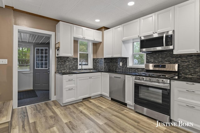 2264 Stafford Ave SW, Grand Rapids, MI 49507 - kitchen featuring stainless steel appliances, a sink, light wood finished floors, dark countertops, and recessed lighting