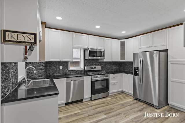 2264 Stafford Ave SW, Grand Rapids, MI 49507 - kitchen featuring appliances with stainless steel finishes, a sink, white cabinetry, dark countertops, and light wood finished floors