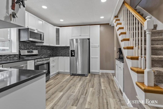2264 Stafford Ave SW, Grand Rapids, MI 49507 - kitchen featuring stainless steel appliances, dark countertops, white cabinets, decorative backsplash, and recessed lighting
