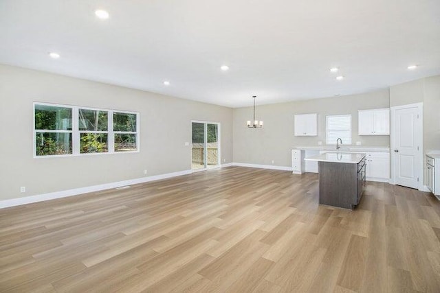6218 Sturgeon Run, Muskegon, MI 49444 - unfurnished living room featuring a chandelier, a sink, light wood-style floors, recessed lighting, and baseboards