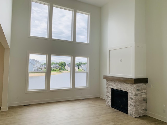 15765 Norwalk Rd, Grand Haven, MI 49417 - unfurnished living room with light wood-style flooring, a fireplace, plenty of natural light, and a towering ceiling