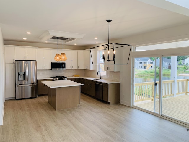 15765 Norwalk Rd, Grand Haven, MI 49417 - kitchen with stainless steel appliances, light countertops, light wood-type flooring, a kitchen island, and decorative backsplash