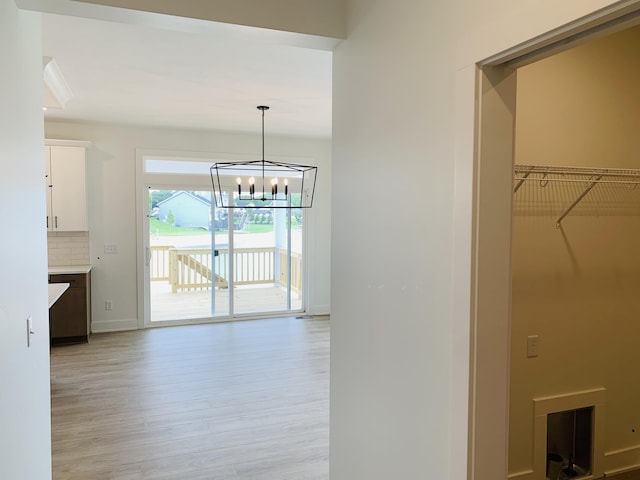 15765 Norwalk Rd, Grand Haven, MI 49417 - corridor featuring light wood finished floors and a chandelier