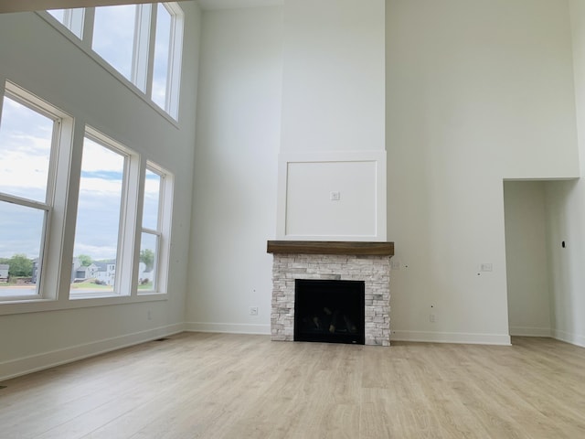 15765 Norwalk Rd, Grand Haven, MI 49417 - unfurnished living room featuring a high ceiling, light wood-style floors, and a fireplace