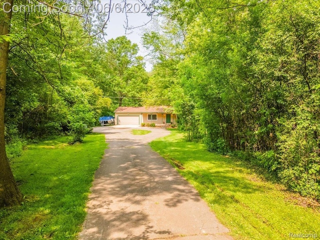 22850 Sumpter Rd, Belleville, MI 48111 - view of front of house featuring asphalt driveway, a wooded view, an attached garage, and a front yard