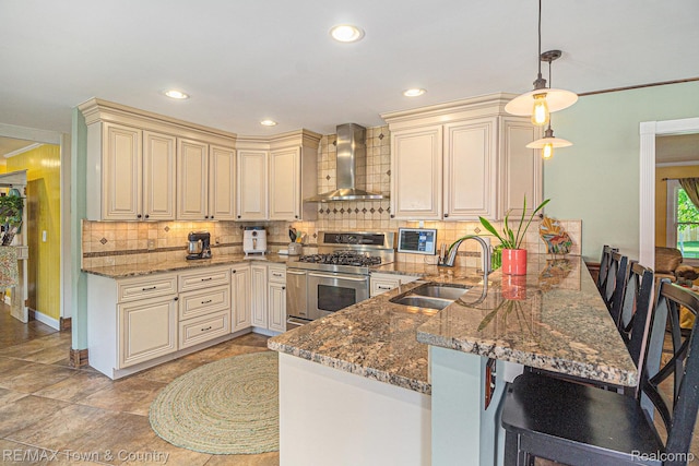 813 Birchwood Dr, Flushing, MI 48433 - kitchen featuring wall chimney range hood, double oven range, cream cabinets, a sink, and a peninsula