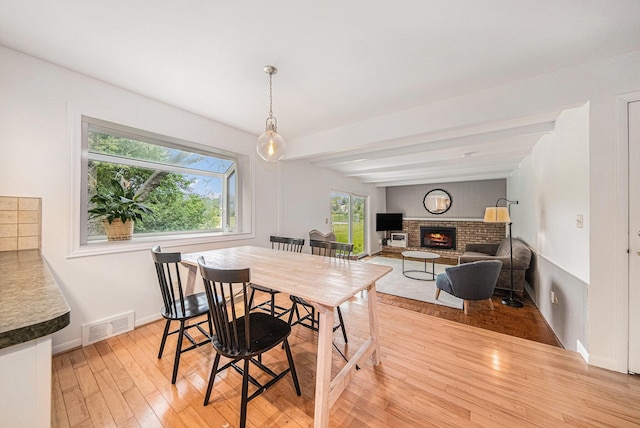 2402 Victoria Ave, Ann Arbor, MI 48104 - dining area featuring light wood-style floors, a brick fireplace, beamed ceiling, and baseboards