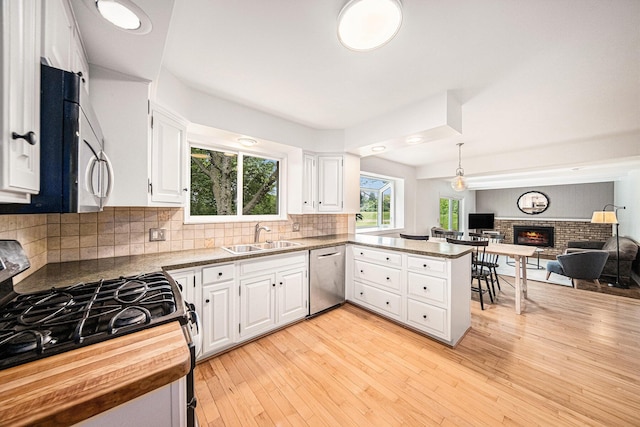 2402 Victoria Ave, Ann Arbor, MI 48104 - kitchen with appliances with stainless steel finishes, a sink, open floor plan, a peninsula, and white cabinets