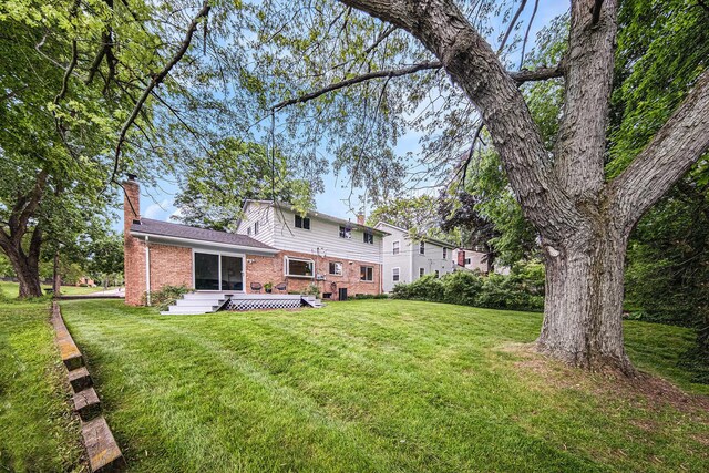 2402 Victoria Ave, Ann Arbor, MI 48104 - rear view of house featuring a chimney, brick siding, a lawn, and a deck