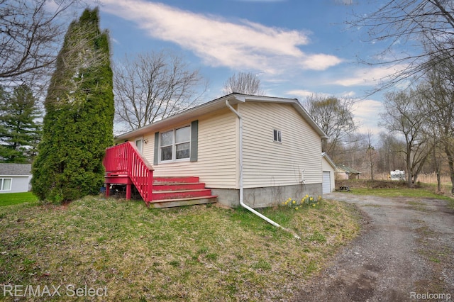 10304 Nichols Rd, Montrose, MI 48457 - view of side of home with asphalt driveway, a garage, and a yard