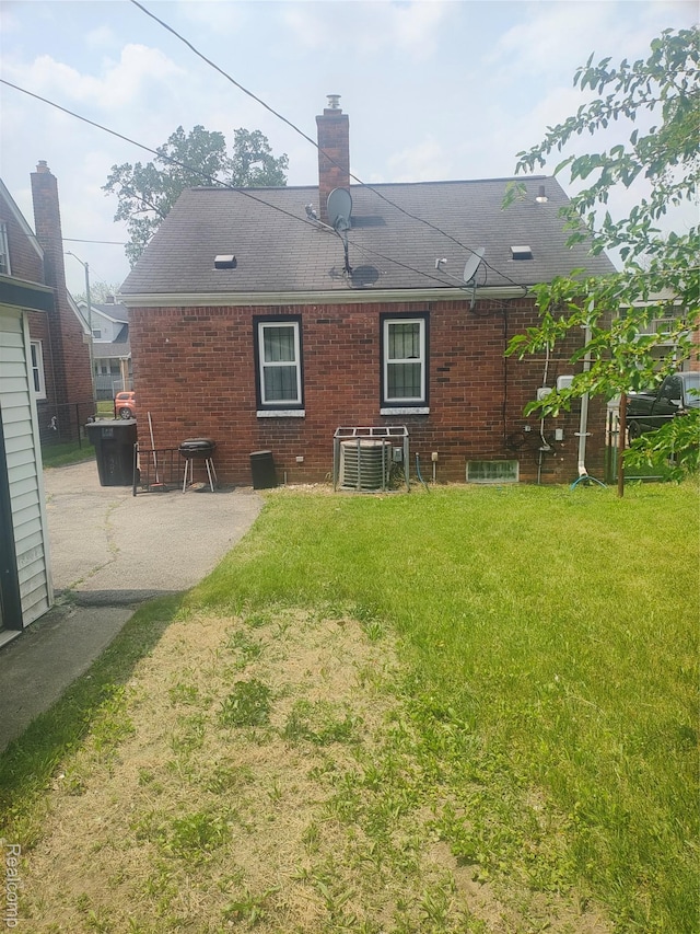 20022 Hanna St, Highland Park, MI 48203 - back of house featuring a lawn, a patio, a chimney, brick siding, and roof with shingles