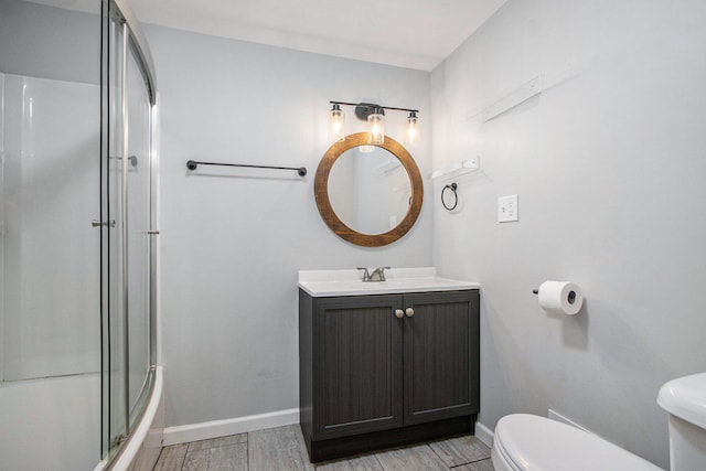 854 Upton Ave, Battle Creek, MI 49037 - bathroom featuring toilet, vanity, a shower with door, wood finished floors, and baseboards