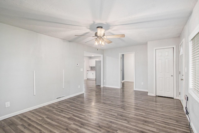 854 Upton Ave, Battle Creek, MI 49037 - unfurnished living room with a ceiling fan, dark wood-type flooring, baseboards, and a textured ceiling
