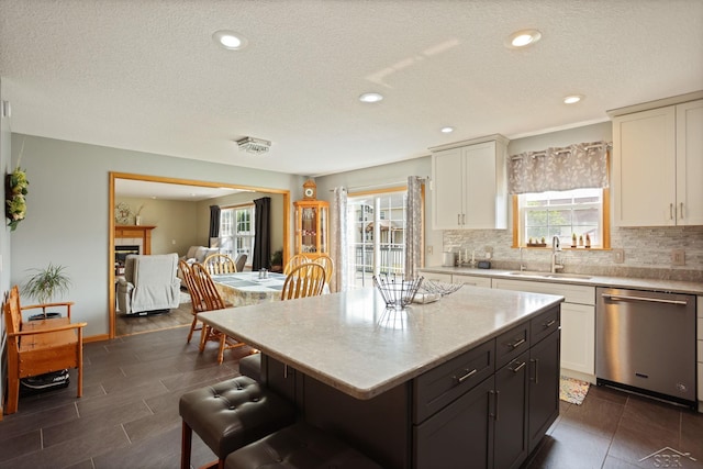 3156 Sundown Ln, Saginaw, MI 48603 - kitchen featuring stainless steel dishwasher, a sink, plenty of natural light, a kitchen breakfast bar, and a textured ceiling