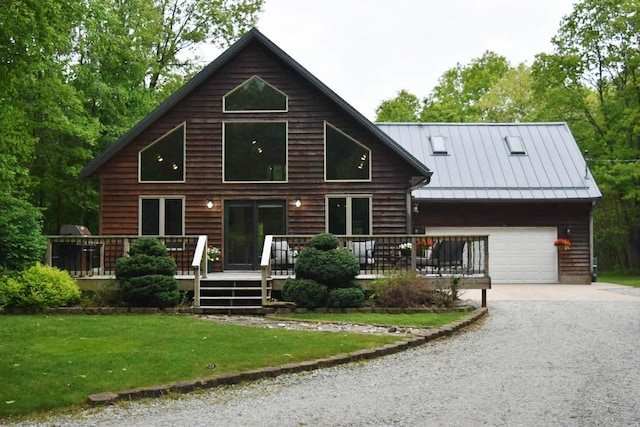 2735 Nestrom Rd, Muskegon, MI 49445 - view of front of home with gravel driveway, an attached garage, a deck, a front lawn, and a standing seam roof