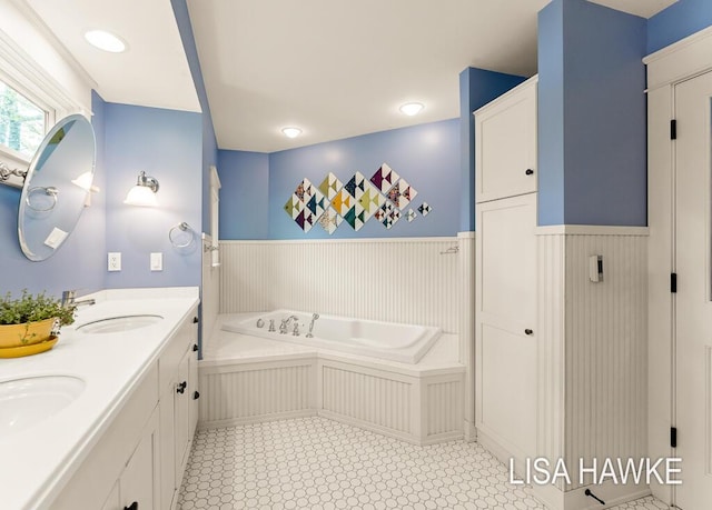 12857 Wilderness Trl, Grand Haven, MI 49417 - bathroom with wainscoting, a bath, and double vanity