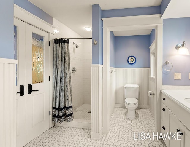 12857 Wilderness Trl, Grand Haven, MI 49417 - full bath featuring a tile shower, toilet, vanity, tile patterned flooring, and a wainscoted wall