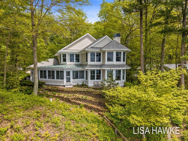 12857 Wilderness Trl, Grand Haven, MI 49417 - view of front of house with a chimney, a sunroom, and a shingled roof