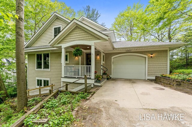 12857 Wilderness Trl, Grand Haven, MI 49417 - view of front of property featuring roof with shingles, a garage, driveway, and covered porch